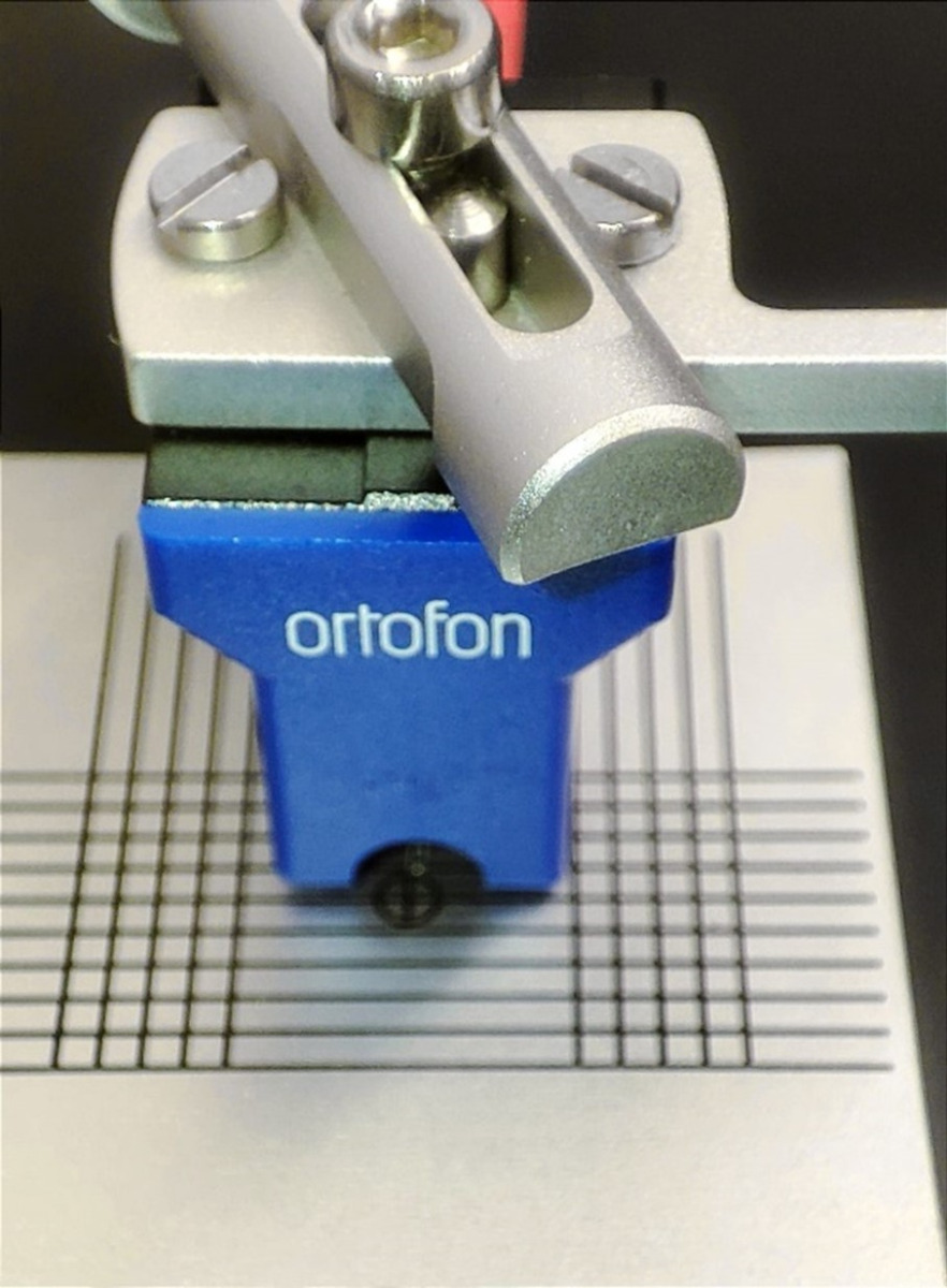 Cartridge alignment protractor placed on turntable platter showing the correct alignment position with stylus at crosshair